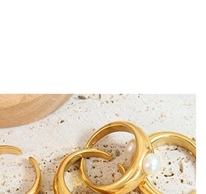 Detailed macro shot of adjustable gold rings with a single white pearl on stone surface