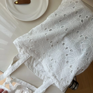 Detail of white cotton tote bag featuring intricate floral embroidery and eyelet lace texture