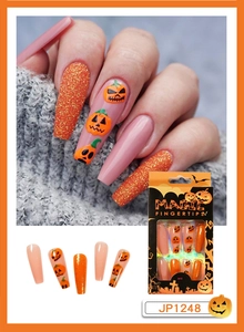 Detail of Halloween press on nails with orange pumpkin faces and glitter on long coffin shape