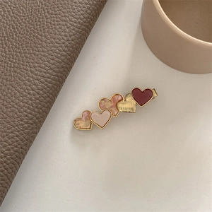 Detailed macro view of heart-shaped acetate hair clips in burgundy and pink colors