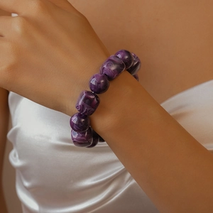 Macro detail of purple marbled acrylic beaded bracelet worn on a female wrist