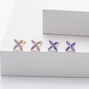 Detailed view of silver and gold flower stud earrings with purple marquise gemstones