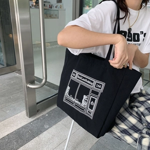 Detail shot of a black canvas tote bag featuring a white bookstore graphic print design