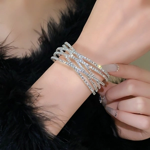 Detailopname van de luxe zilveren wikkelarmband met fonkelende strassteentjes om de pols
