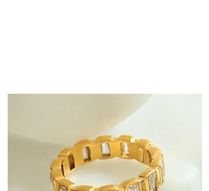 Close-up of a gold ring featuring a rectangular transparent zircon on a white background