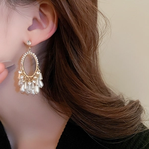 Gros plan de créoles ovales dorées avec cristaux et perles pendantes sur un mannequin