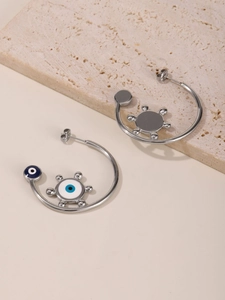 Macro view of silver hoop earrings featuring blue enamel evil eye charms and star motifs