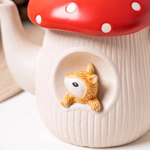 Detail view of a mushroom ceramic teapot with a cute squirrel window and red spotted lid