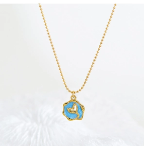 Detailed macro view of the gold beaded chain and blue enamel dolphin tail pendant