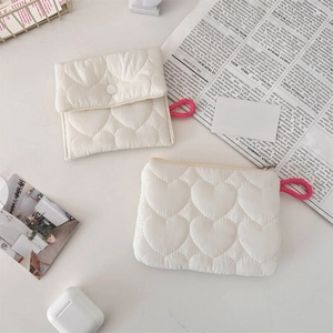 Detail view of quilted heart pattern small white storage pouches with pink strap accents