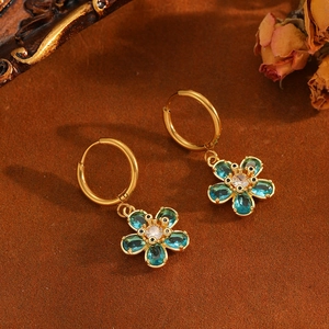 Gros plan détaillé des boucles d'oreilles dorées avec fleurs bleues et pierres brillantes