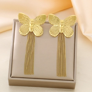 Macro view of gold butterfly tassel earrings hanging on jewelry box with silk background
