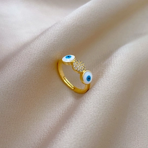 Detailed view of evil eye ring with blue enamel and pave zircons on beige satin