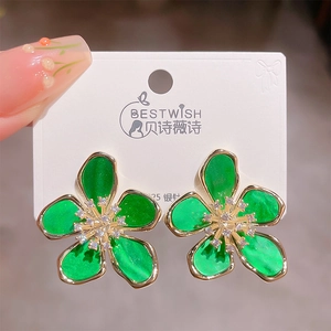 Detailed macro shot of 925 silver green enamel flower earrings with zircon center