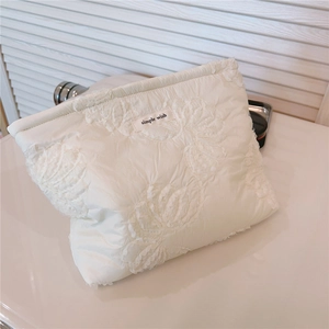 Detailed view of quilted lace floral pattern on a cream white soft cosmetic bag
