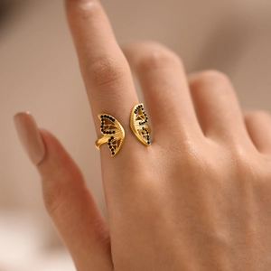 Adjustable golden butterfly ring with black diamond inlay for women on a model hand