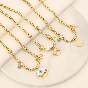Detail of gold evil eye and cross bracelets on a white marble tray background