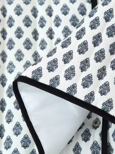 Macro detail of leaf print quilted jacket showing stitching and black piping trim