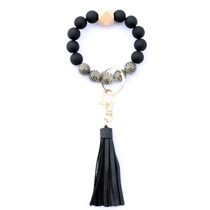 Close-up of matte black and polka dot beads with leather tassel on a metal keychain ring