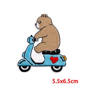 Detail of embroidered brown bear on a light blue scooter with a red heart patch