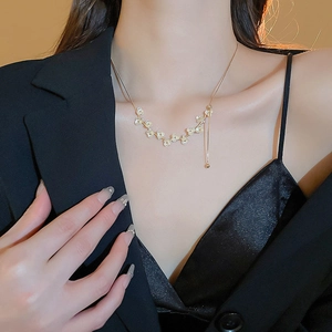 Dettaglio di elegante collana a fiori placcata oro con perle indossata dalla modella