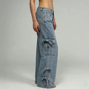 Detail view of light blue wide-leg jeans with a decorative bow on the side cargo pocket