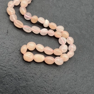 Macro detail of natural irregular rose quartz beads on a textured dark stone background