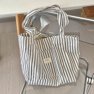 Detail of blue and white striped canvas tote bag with front pocket on a chair