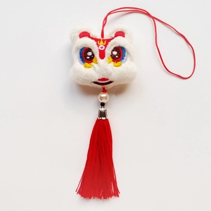 Détail d'un pendentif lion en peluche avec pompons rouges, perles et capuchon en argent