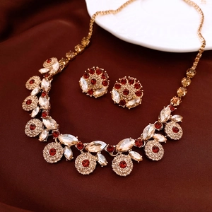 Detail of vintage gold-tone jewelry set with red gemstones and floral crystal pattern