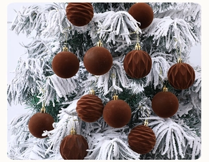 Detailed view of 6cm brown flocked velvet Christmas balls hanging on a snowy tree branch