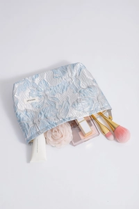 Detailed view of the jacquard floral makeup bag with cosmetics inside for storage