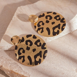 Détail de boucles d'oreilles rondes dorées avec motif léopard sur pierre naturelle