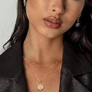 Détail d'un collier doré à deux rangs et pendentif hexagonal lettre S sur un mannequin