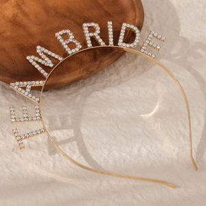 Detailed view of gold TEAM BRIDE headband with sparkling rhinestones on beige background