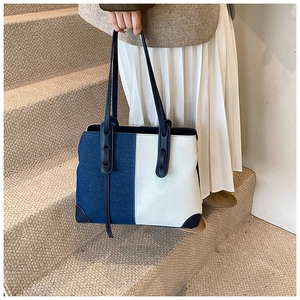 Detail view of denim patchwork tote bag with blue handles on a staircase setting
