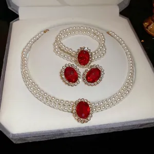 Elegant pearl necklace set featuring oval red gemstone pendants and sparkling rhinestones
