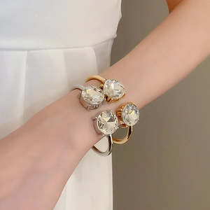 Close-up of gold and silver open bangles with large faceted crystal stones on a wrist