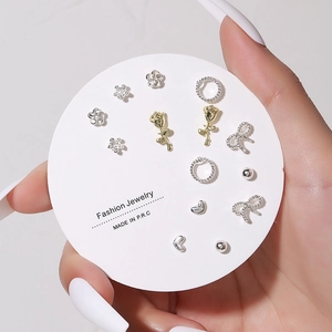Close-up of floral and heart stud earring set displayed on a round fashion card
