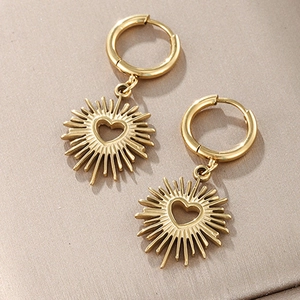 Détail de boucles d'oreilles cœur doré avec pendentif soleil et fini poli brillant