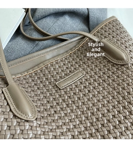 Detail of tan woven leather tote bag with embossed logo and elegant shoulder strap