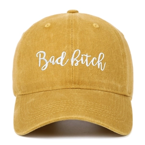 Close-up of 'Bad Bitch' white embroidery on washed cotton mustard yellow baseball cap