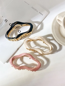Three metal shark hair clips with irregular wave patterns in black, cream, and pink colors