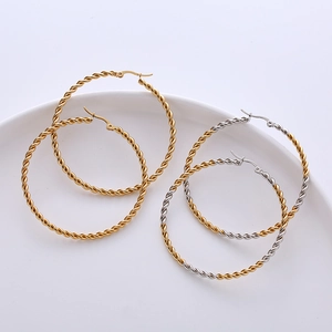 Pendientes de aro retorcidos de 50 mm en oro y bicolor sobre una bandeja blanca