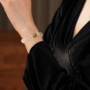 Gros plan de perles de cristal blanc et pierre verte sur bracelet en santal au poignet