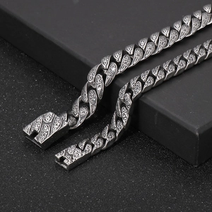 Close-up of vintage engraved Cuban link bracelet with antique silver finish on a black pedestal