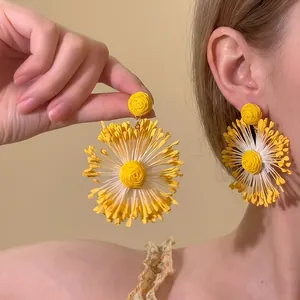 Close-up of bright yellow large floral drop earrings with a stylish oversized design