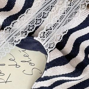 Gros plan sur la texture de toile rayée et les détails en dentelle florale du sac à main