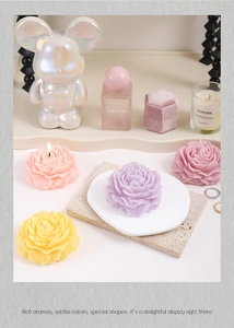 Detailed close-up of pink, purple, and yellow peony-shaped soy candles in a gift setting