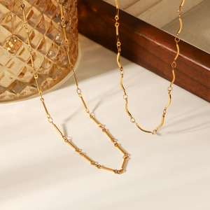 Collier artisanal en acier inoxydable doré à maillons barres sur un support élégant